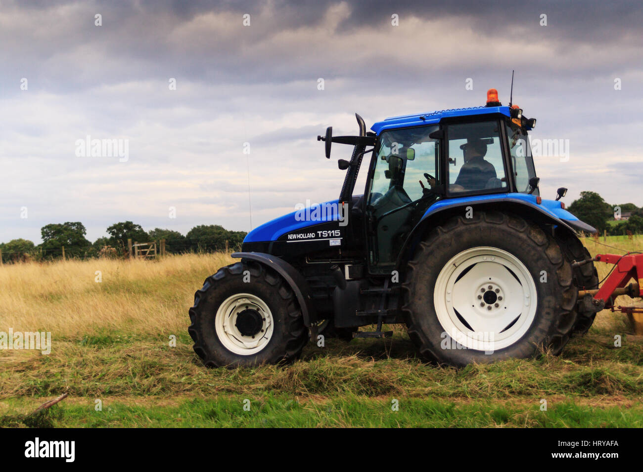 Landwirt schneiden Heu von Wiese mit topper oder Grass Cutter in einem Feld im ländlichen Shropshire UK Stockfoto