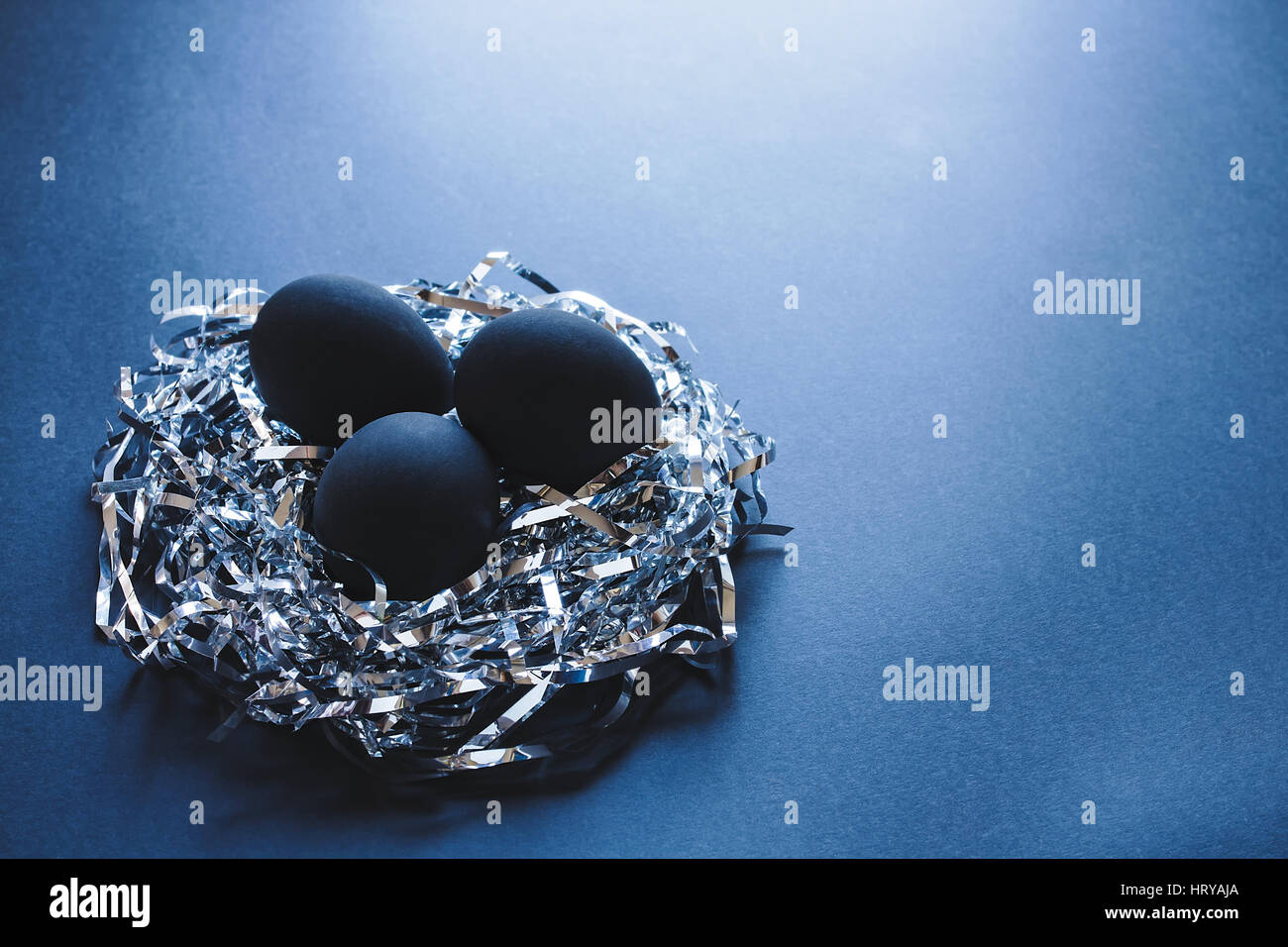 Drei schwarzen Eiern in einem Nest gemacht von silbernen Saiten auf dunkelblauem Hintergrund, Ostern-Konzept Stockfoto