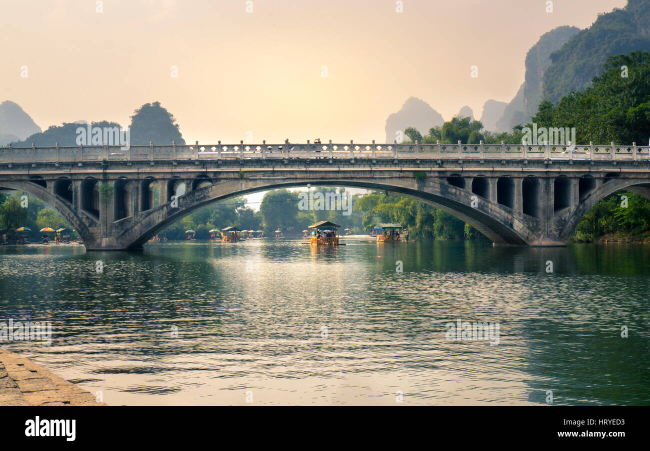 YANGSHUO, CHINA - 23. September 2016: Boote mit Touristen auf Li-Fluss, unten eine steinerne Brücke bei Sonnenuntergang schwimmen Stockfoto