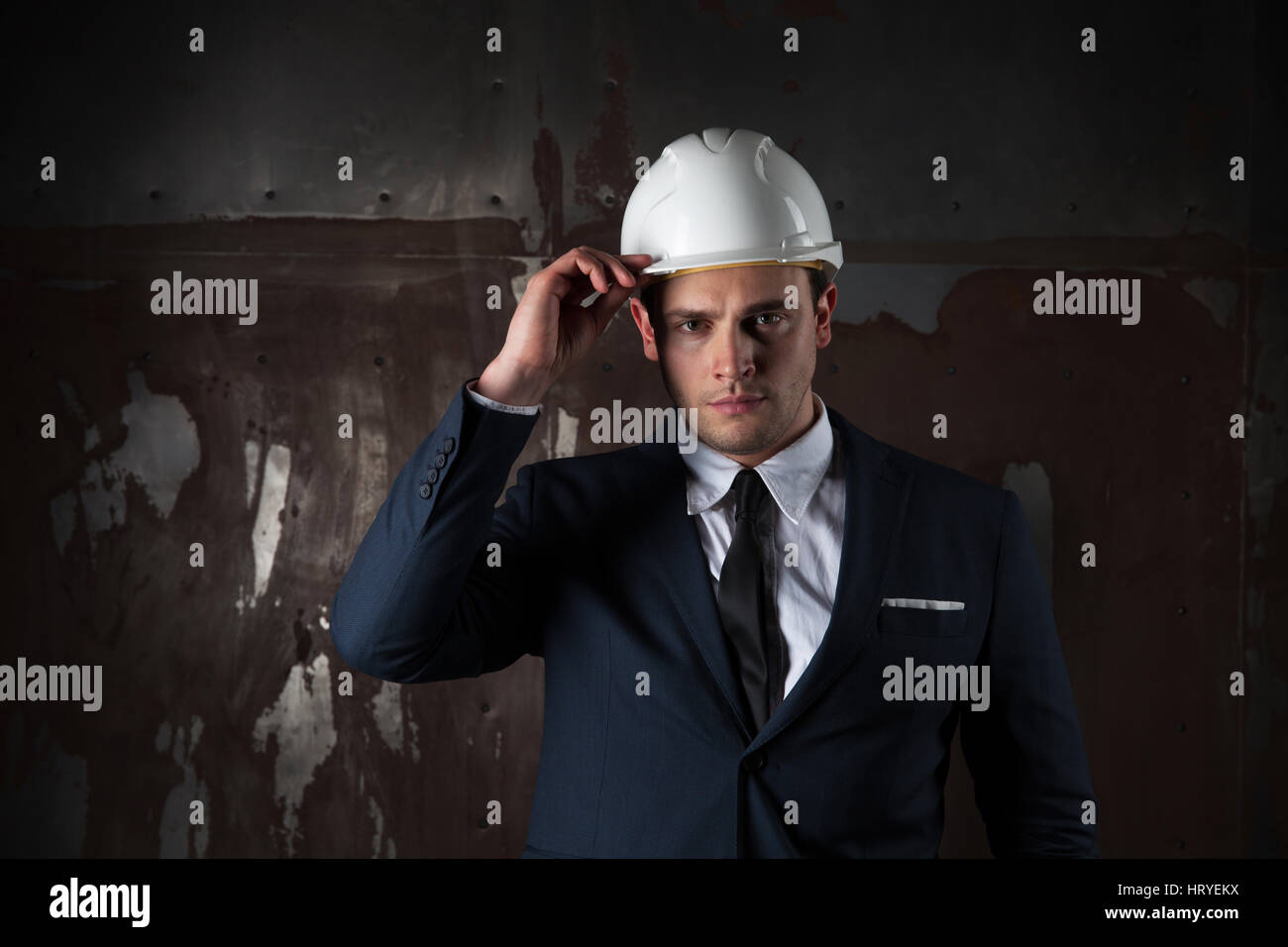 Porträt eines jungen Architekten in industriellen Konzept in weißen Helm und in einem eleganten Anzug auf dunklem Hintergrund Stockfoto