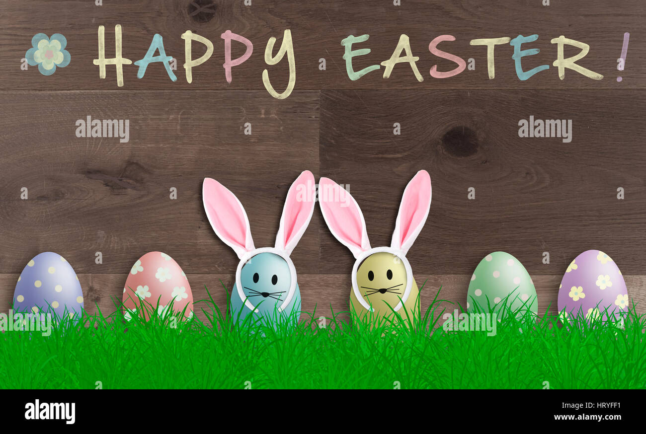 bunte Pastellfarben Ostereier mit Hasenohren auf hölzernen Hintergrund, Werbe Schild mit Text Frohe Ostern Stockfoto
