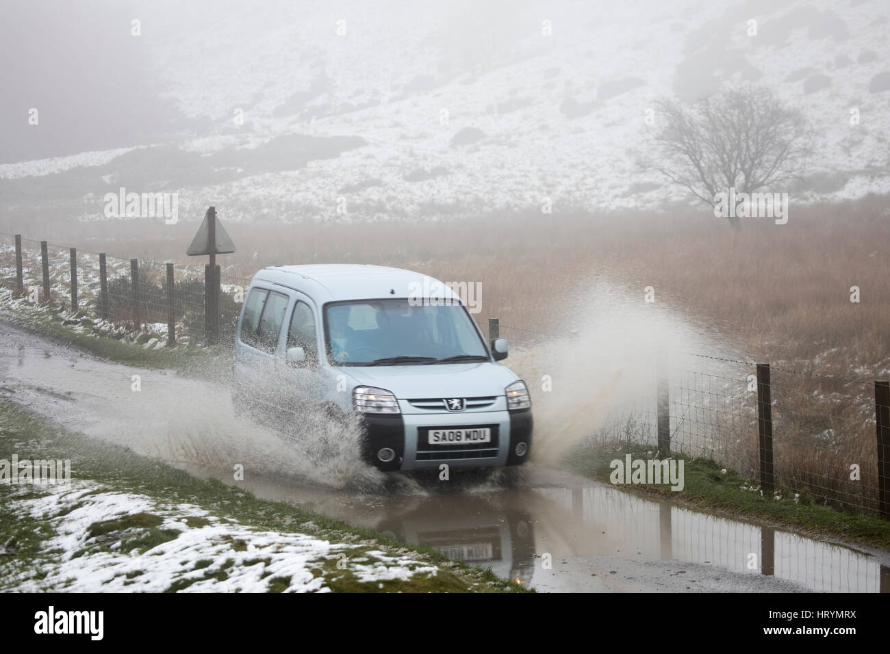 Auto durch Schnee bedeckt und überflutete Straße in die Clwydian Hügel reichen Hügel an der Grenze von Flintshire und Denbighsire neben Moel Arthur, Wales, Großbritannien reisen Stockfoto