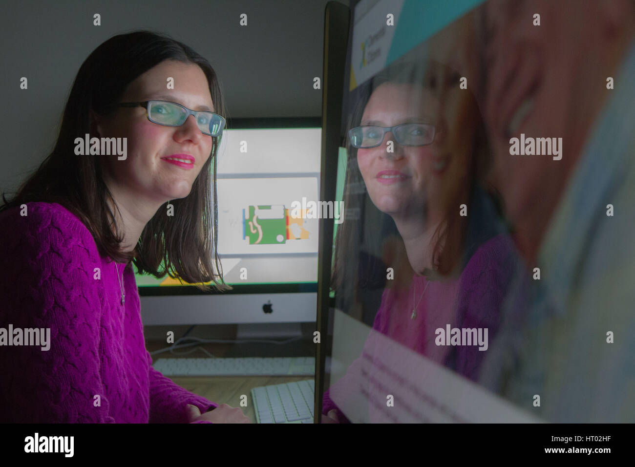 Junge Frau am Computer Bildschirm schaut mit Reflektion Stockfoto