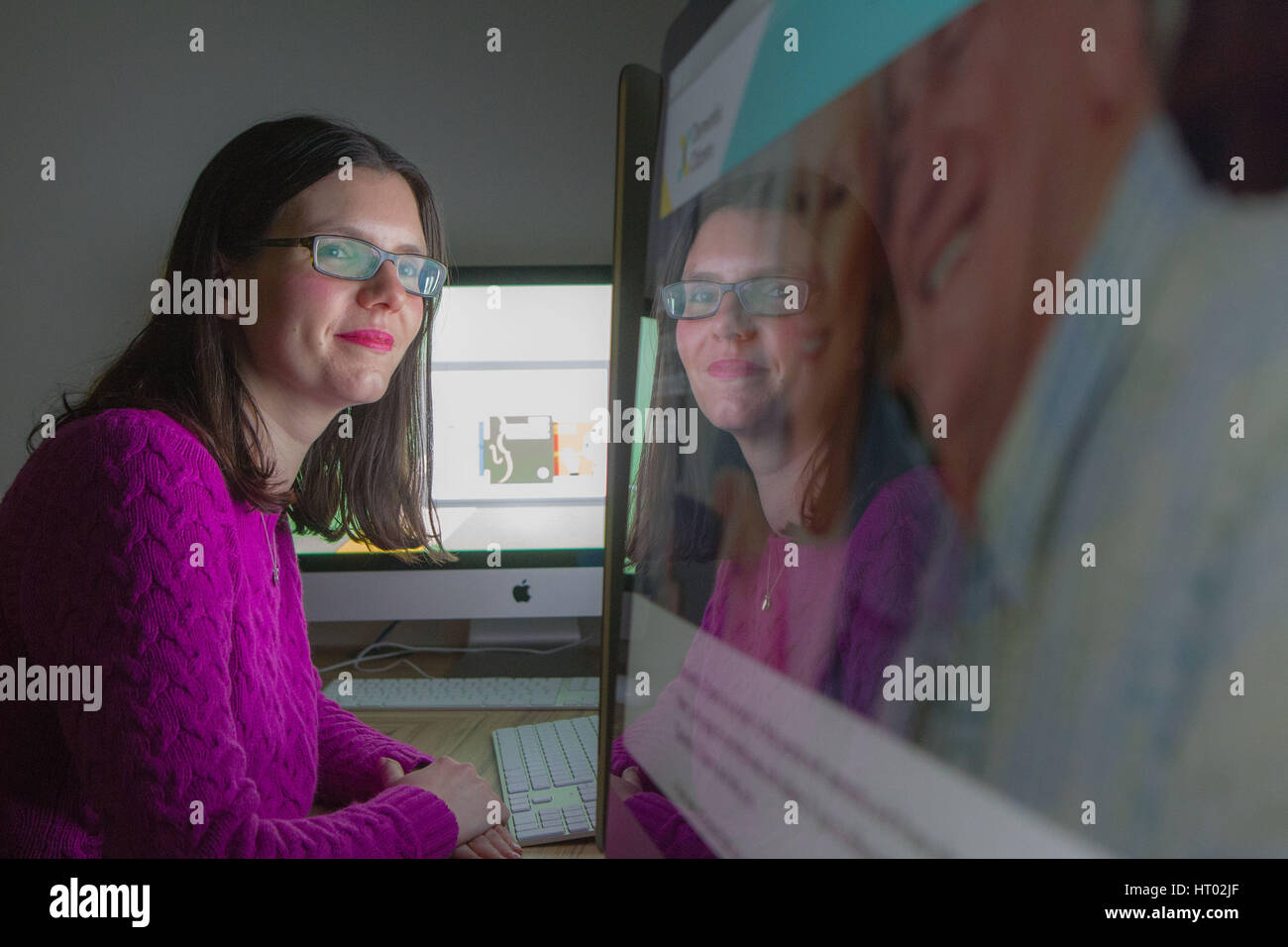 Junge Frau am Computer Bildschirm schaut mit Reflektion Stockfoto