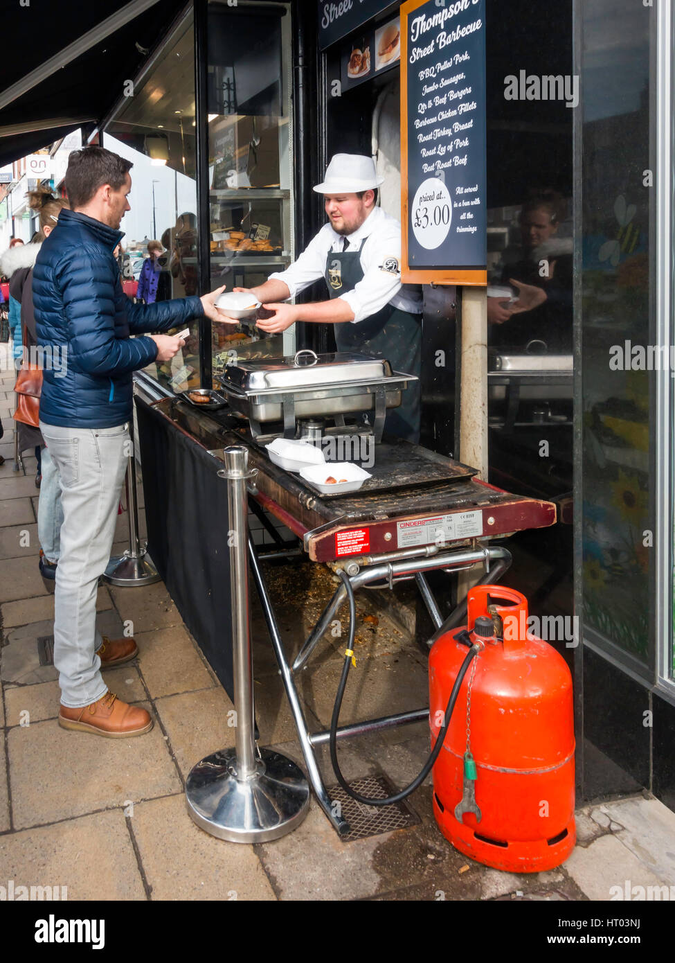 Thompsons Metzger-Shop in Northallerton High Street verkaufen heiße gekochtes Essen zu einem Mann aus einem street Grill auf einem anstrengenden Freitag Markttag Stockfoto