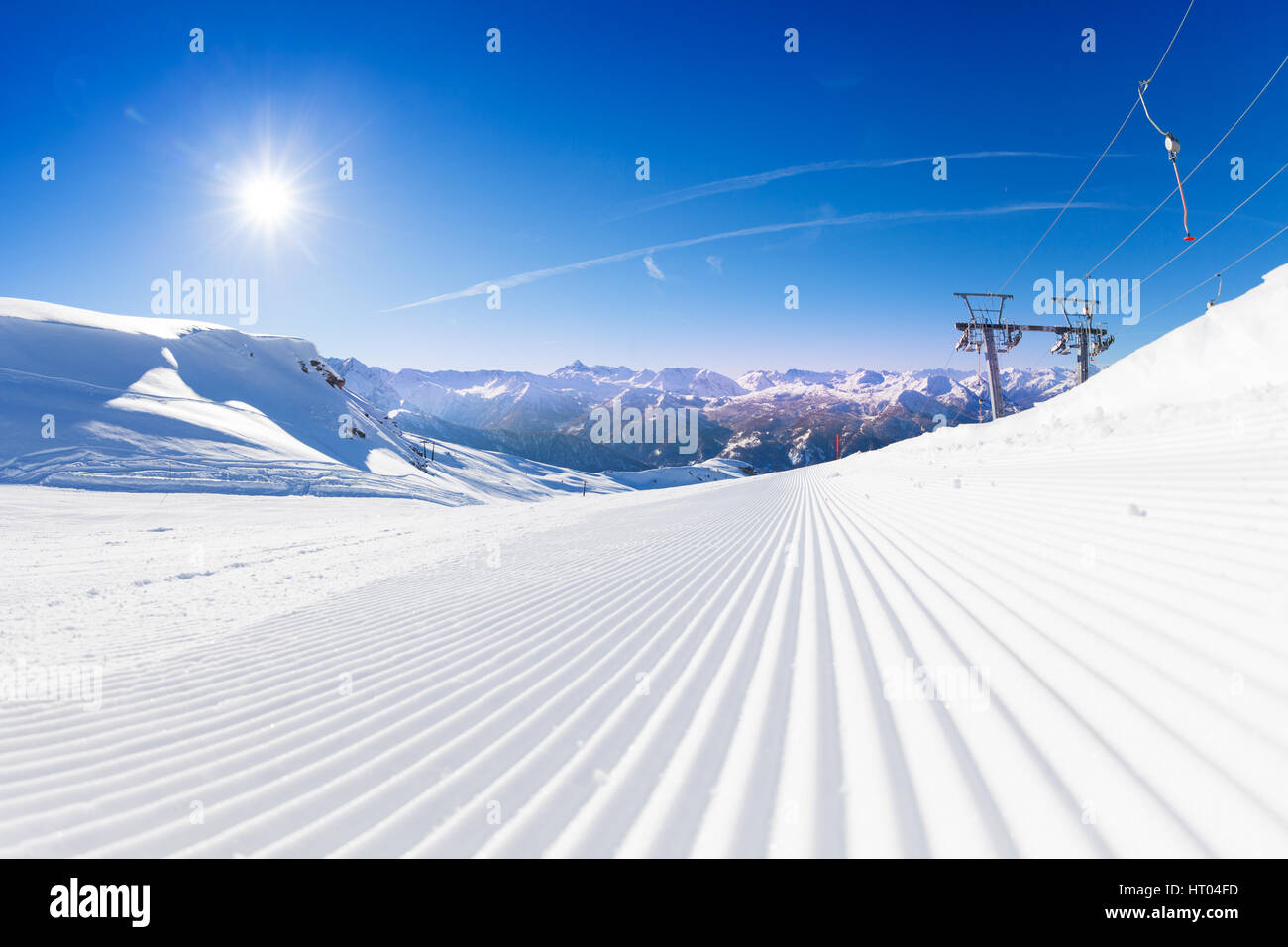 Frische Spuren von Snowcat im Skigebiet Pisten am frühen sonnigen Morgen Stockfoto