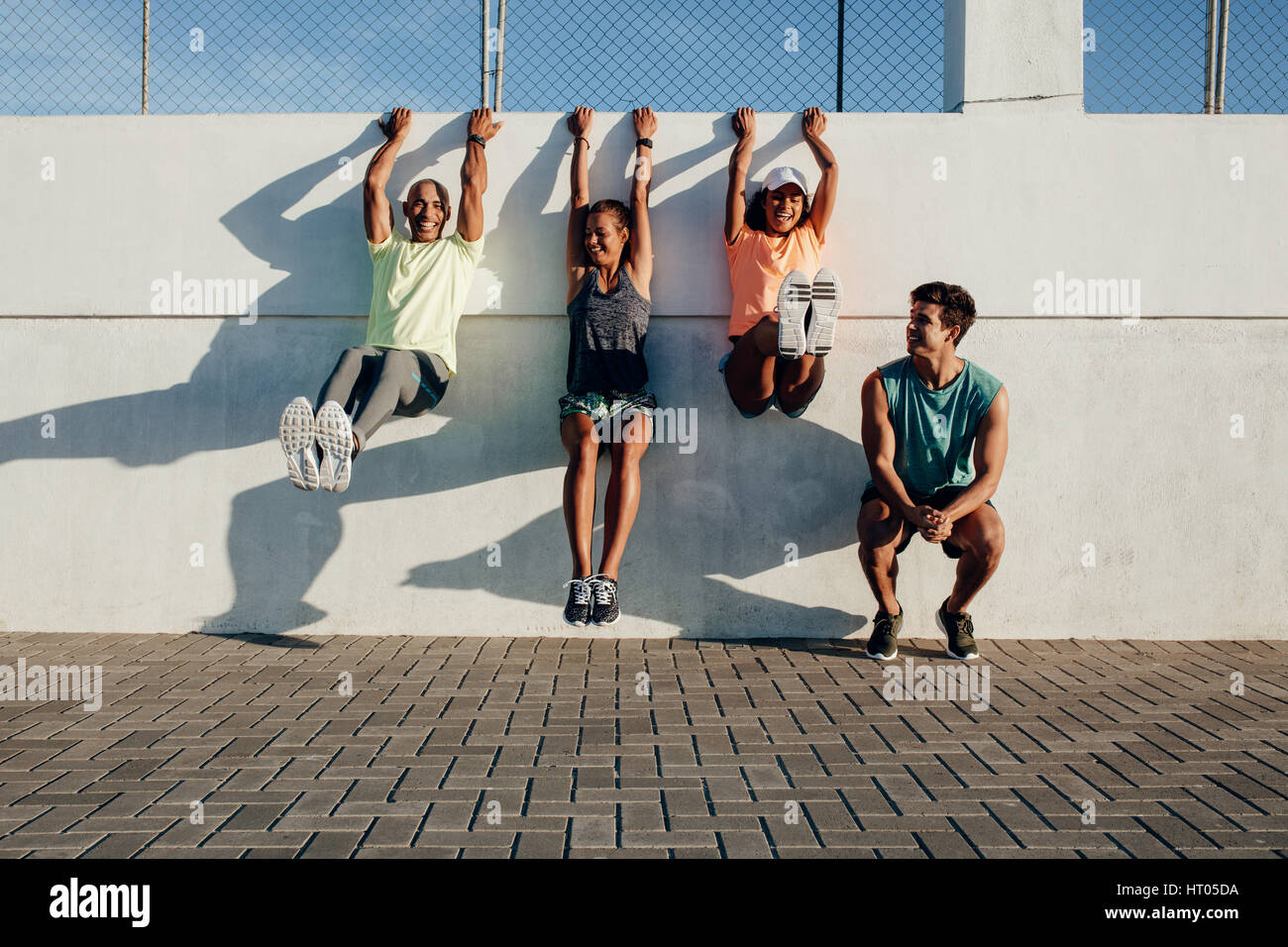 Gruppe von Menschen, die Spaß beim Training Session im Freien. Freunde an der Wand hängen und stretching nach der Sitzung ausgeführt. Stockfoto