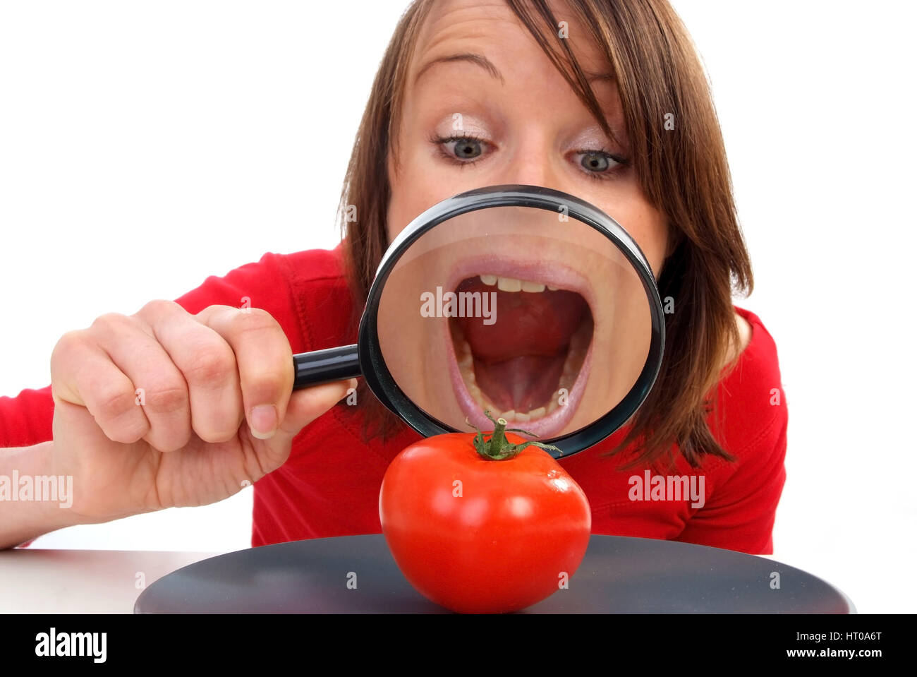 Junge Frau Betrachtet Durch Die Lupe Eine Tomate bin Teller - Frau mit Lupe betrachtet Tomaten auf Teller Stockfoto