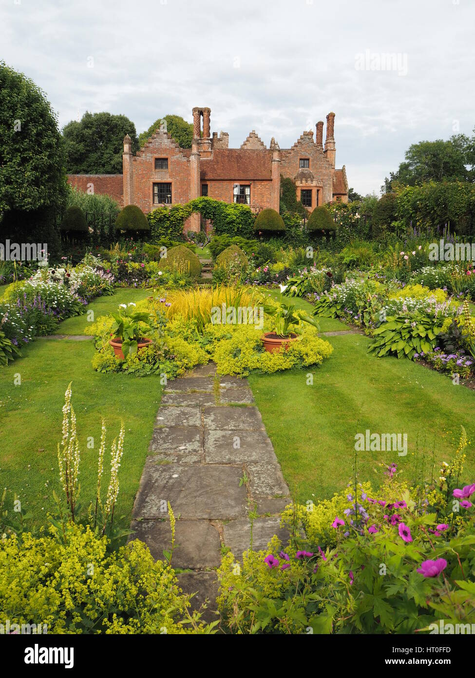 Versunkene Garten im Chenies Manor House Anfang Juli. Üppigen Neuaustrieb, Staudenrabatten, gestreiften Rasen und vorgestellten Zierteich mit Gräsern. Stockfoto