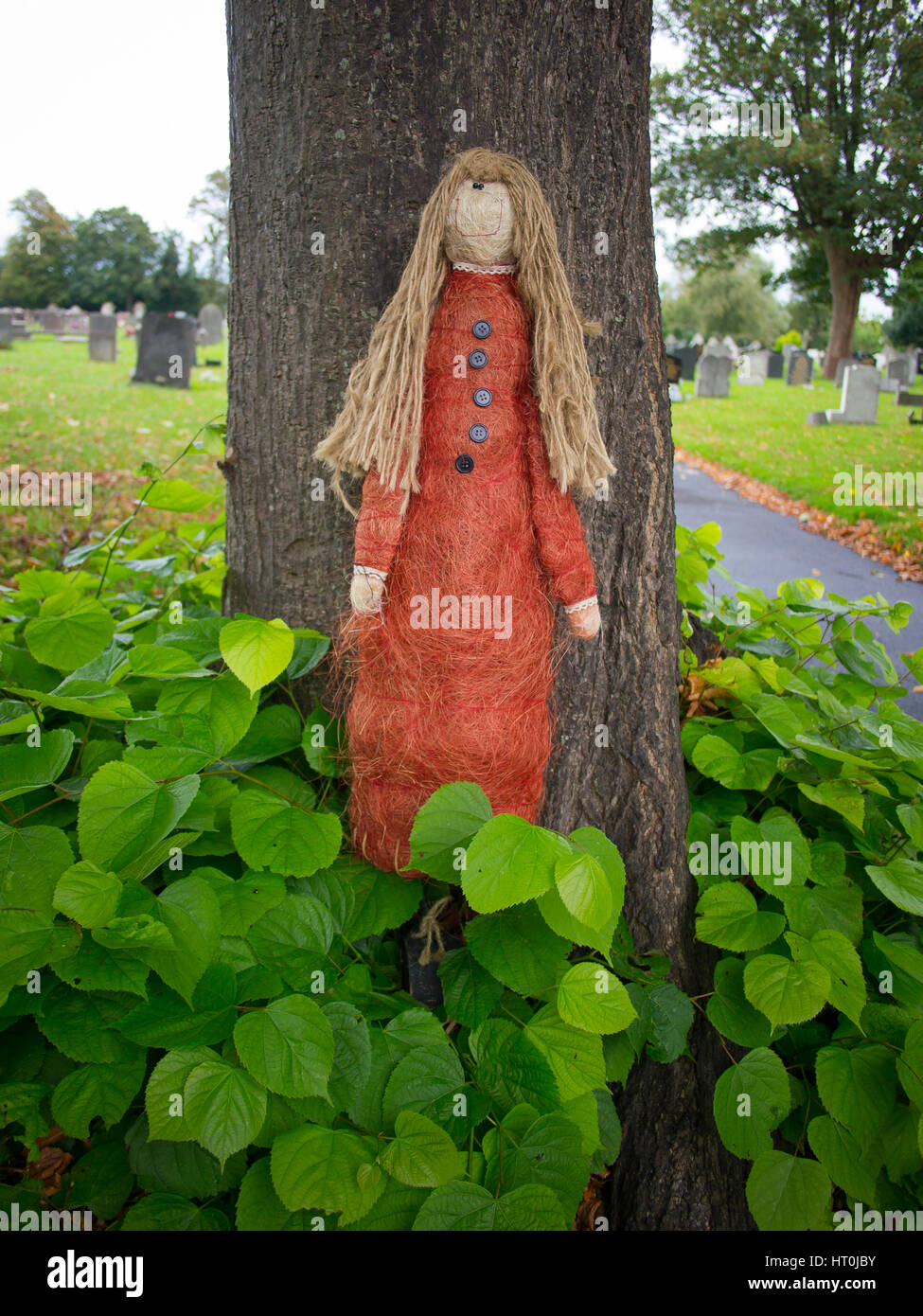 Eine Strohpuppe, die an einem Baum auf einem Friedhof genagelt Stockfoto