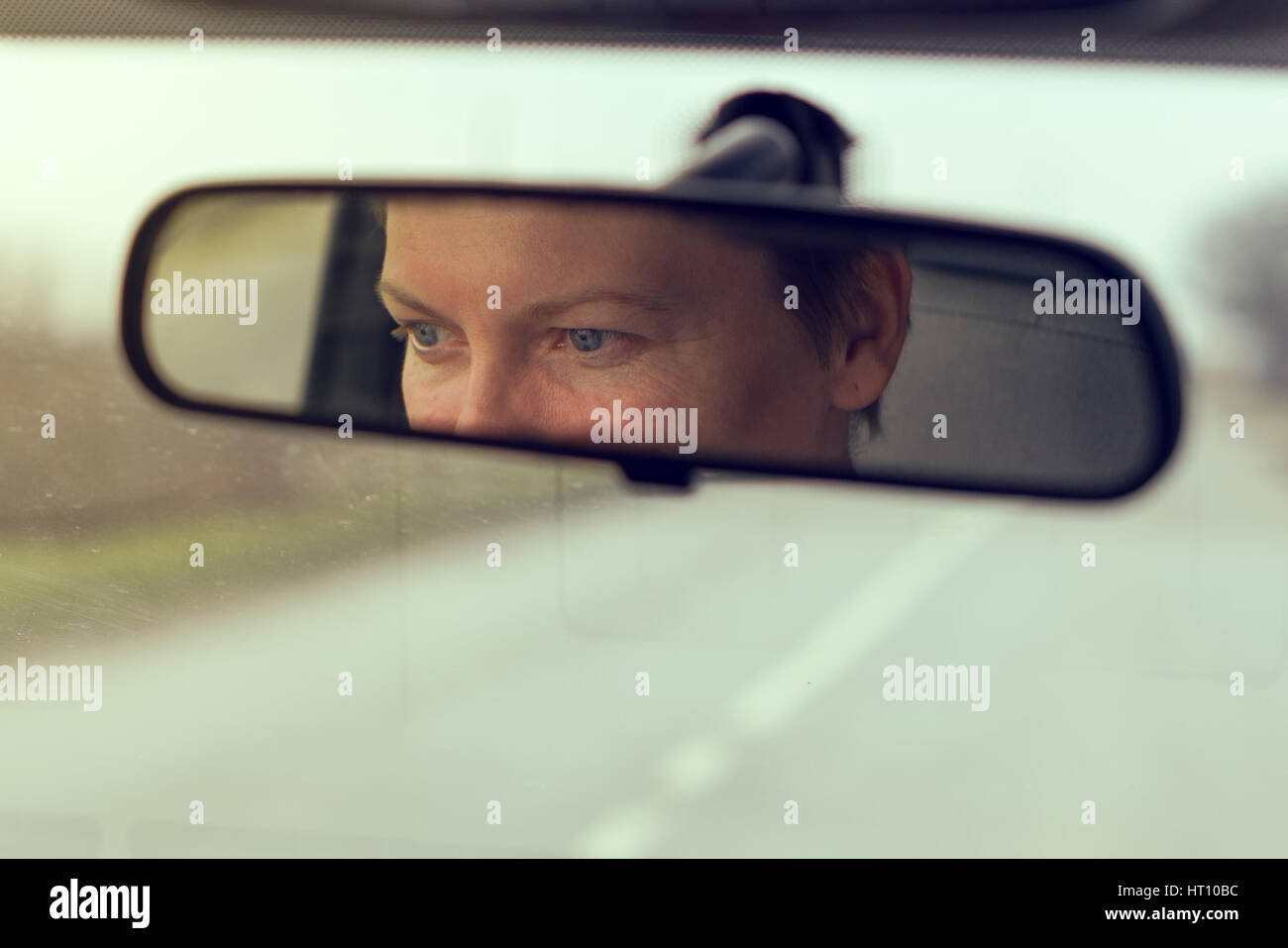 Weiblichen Augen mit Schwerpunkt auf Straße, Reflexion im Fahrzeug Rückspiegel, getönten Retro Bild Stockfoto