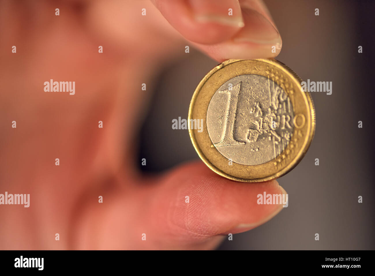 Makroaufnahme einer ein-Euro-Münze zwischen Geschäftsfrau Fingern, EU-Währung Stockfoto