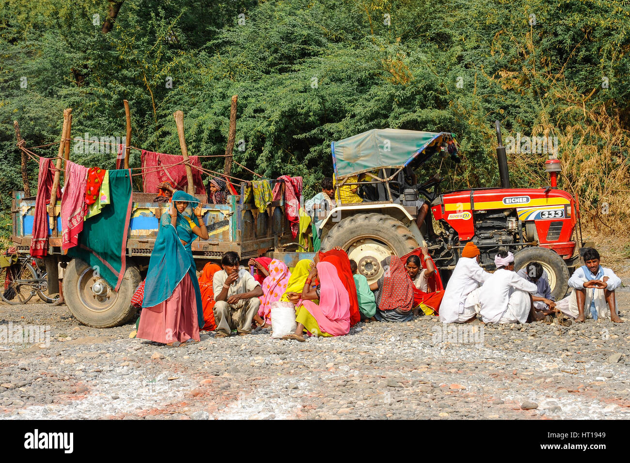 Eine Gruppe von Rajasthani Männer und Frauen sitzen Essen und Reden vor einem Traktor und Anhänger Stockfoto