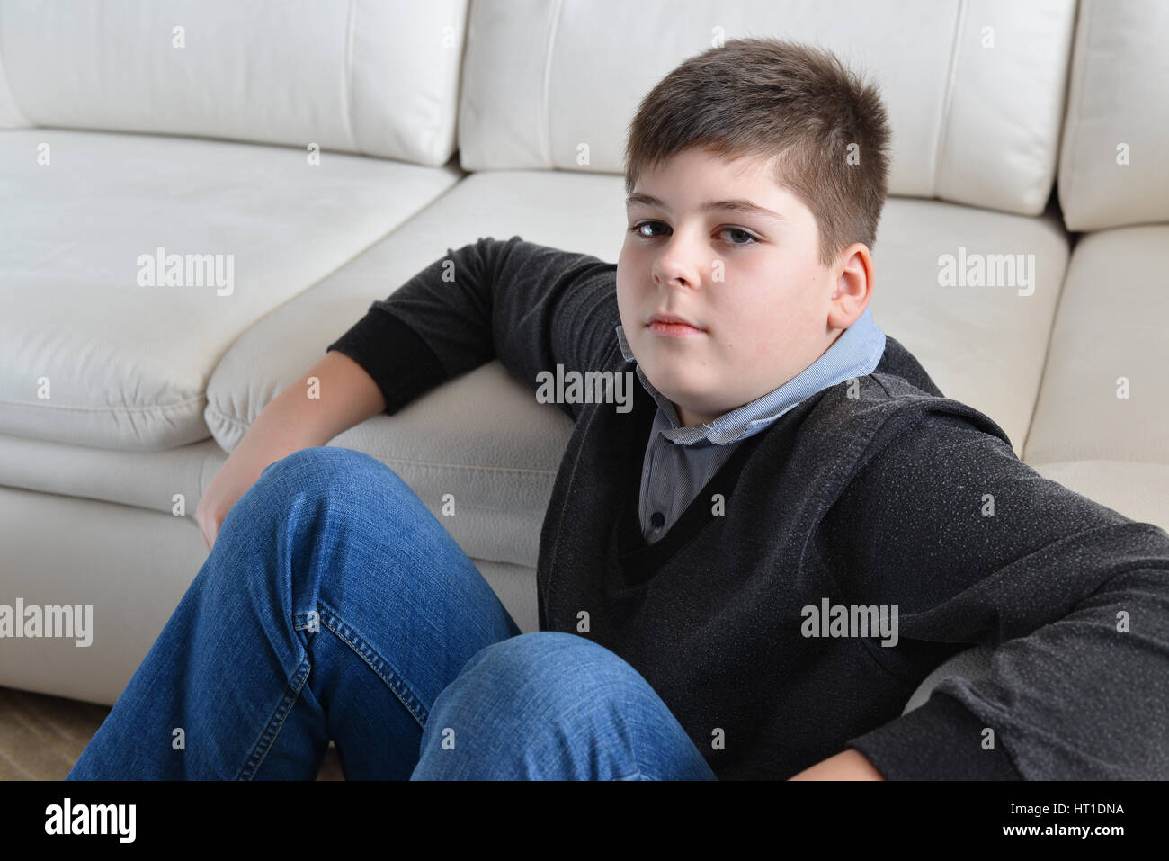 13 Jahre junge sitzt neben dem Sofa im Zimmer Stockfoto, Bild