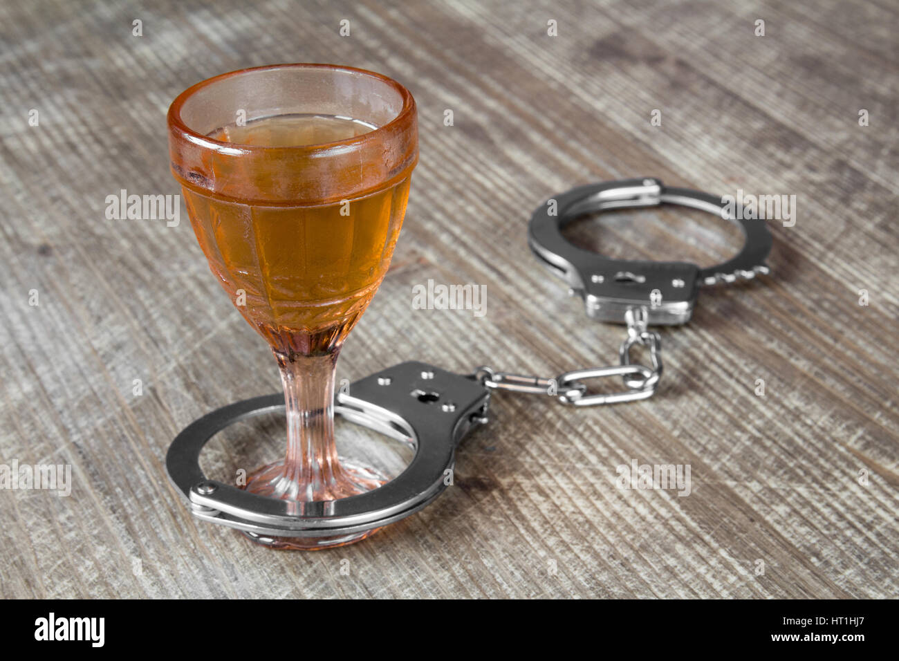 Glas Alkohol mit Handschellen als Symbol für Alkoholmissbrauch Stockfoto