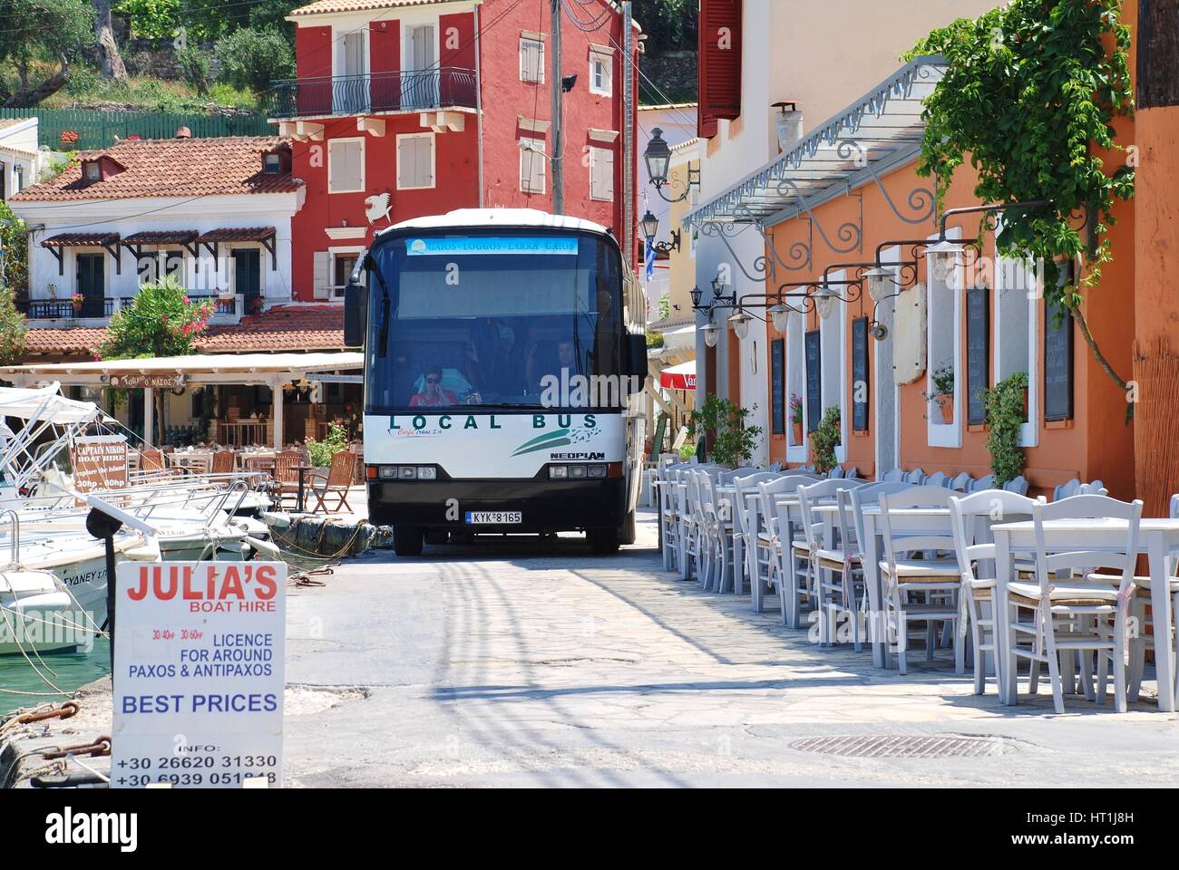 Der Insel-Bus fährt entlang der engen Hafen Straße in Loggos auf der griechischen Insel Paxos. Diners haben oft ihren sitzen zu lassen, durch verlassen. Stockfoto