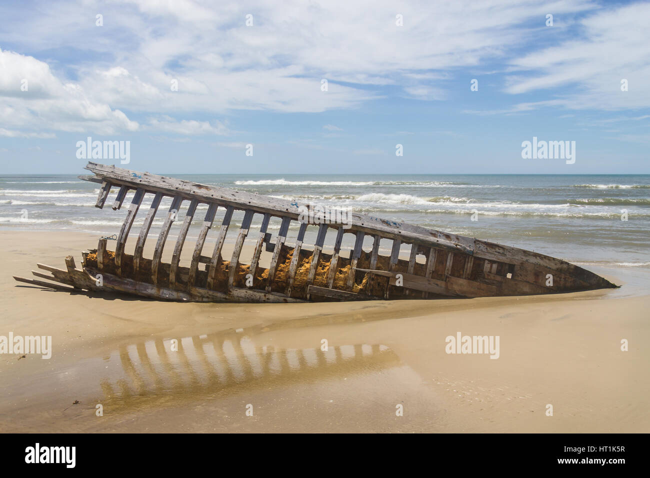 Angelboot/Fischerboot mit Reflexion und Wellen im Hintergrund am Mostardas Beach versenkt Stockfoto