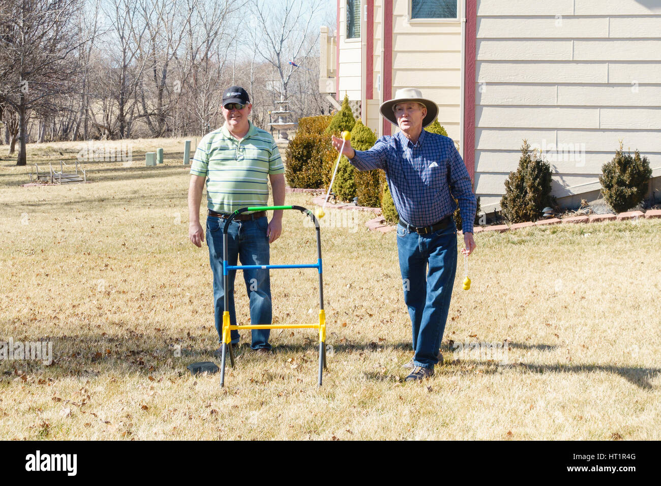 Zwei alte kaukasische Männer spielen Leiter Golf oder Leiter werfen Spiel auf dem Hof. USA. Stockfoto