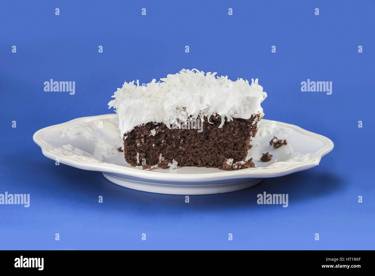 Ein Stück Schokoladenkuchen mit flauschigen weißen Zuckerguss garniert mit Shreded Kokosnuss auf einem weißen Bplate dienen. Oklahoma, USA. Stockfoto