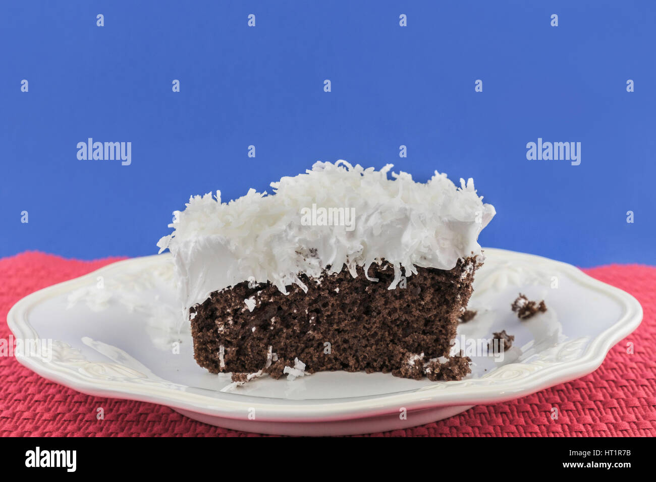 Ein Stück Schokoladenkuchen mit flauschigen weißen Zuckerguss garniert mit Kokosraspeln auf einem weißen Teller. Oklahoma, USA. Stockfoto