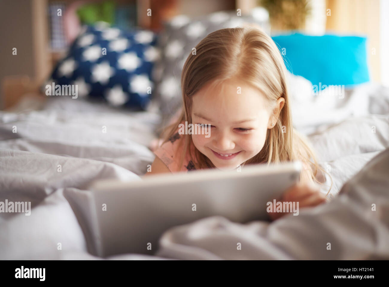 Mädchen mit digital-Tablette im Bett Stockfoto