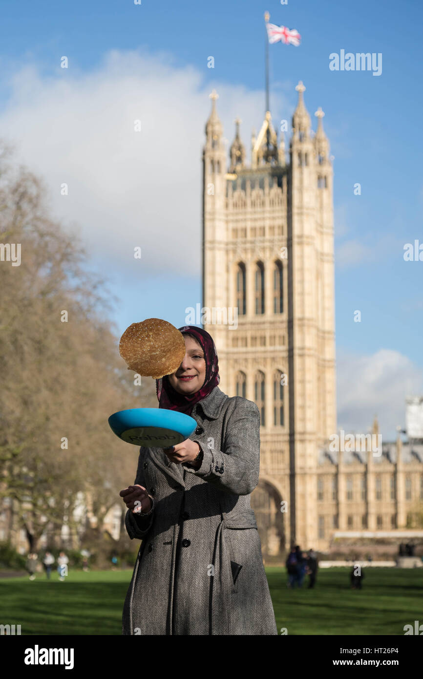 Ein Besucher dreht einen Pfannkuchen im 20. jährlichen parlamentarischen Pfannkuchen Rennen findet am Faschingsdienstag bei Victoria Tower Gardens außerhalb Houses of Parliament in London. Stockfoto