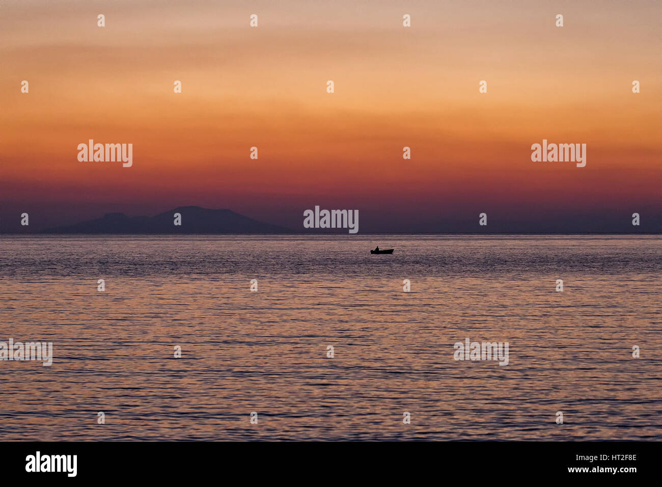 Kleines Boot Sonnenuntergang Silhouette ist ein Fischerboot paddeln entlang des Wassers mit einem bunten lila und rosa Nachthimmel im Hintergrund Stockfoto