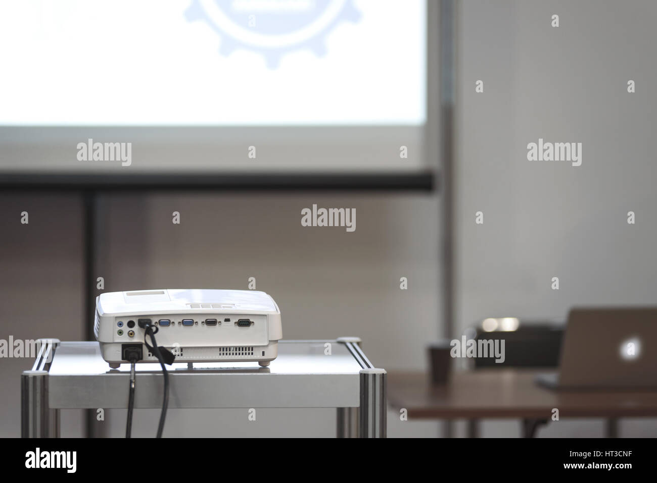 Weiße Multimedia-Projektor in einem Konferenzraum mit Bewegungsunschärfe Projektionsfläche und Dozent Schreibtisch auf dem Hintergrund (reduzierte Ton) Stockfoto