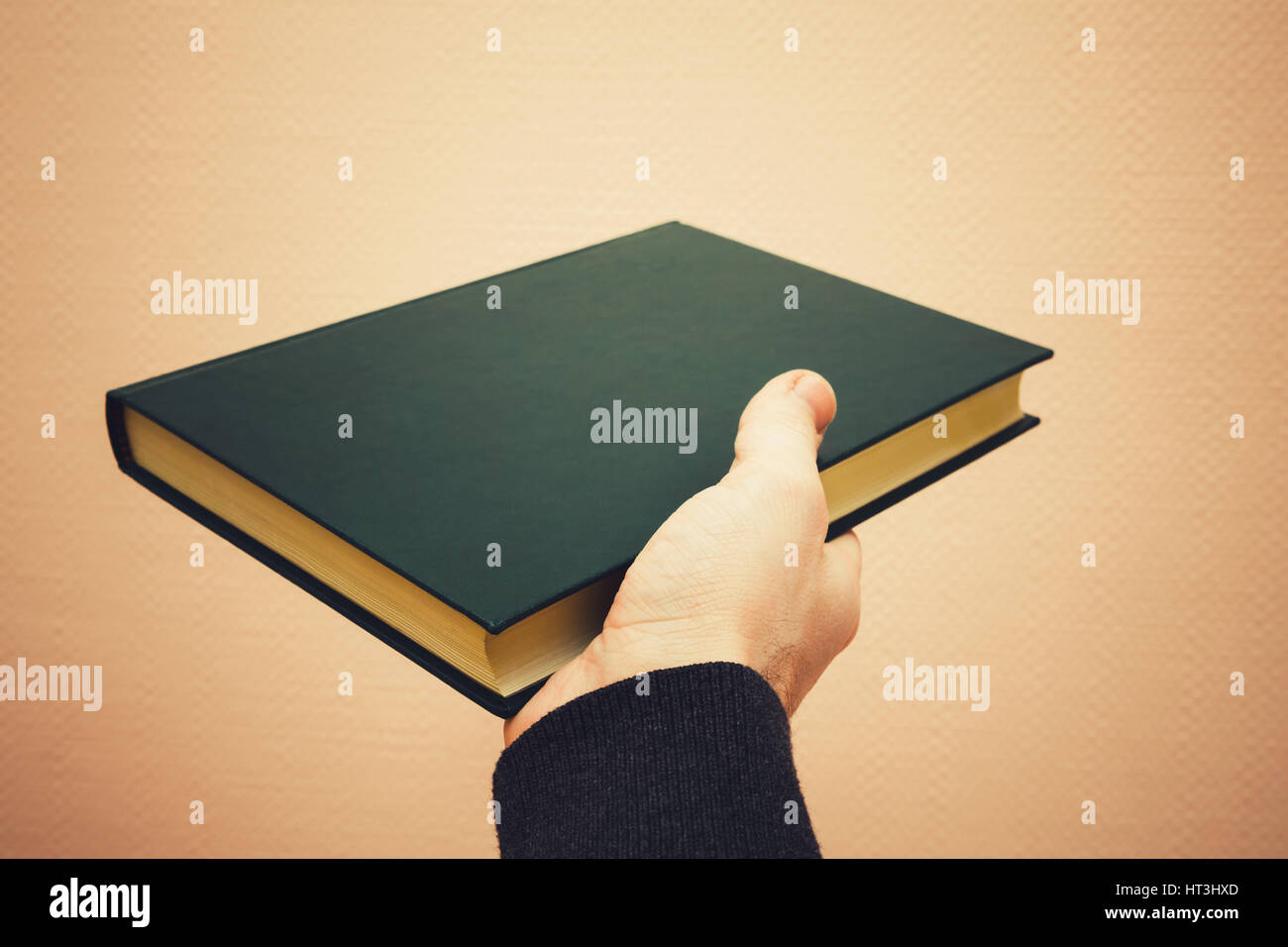 Männliche Hand hält dunkel grünes Buch, Vintage getönten Foto mit selektiven Fokus Stockfoto