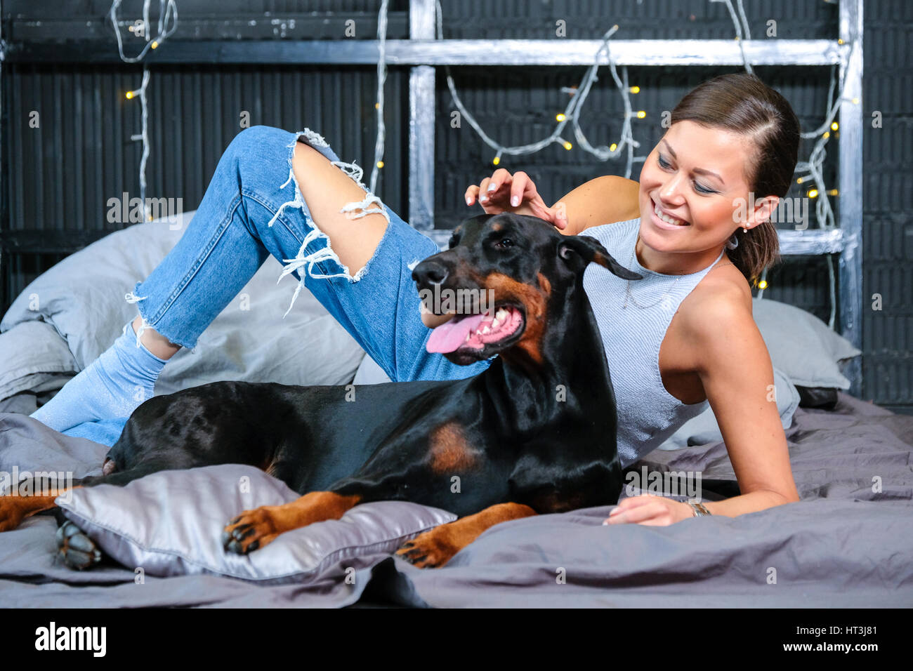 Frau im Bett mit großen schwarzen Dobermann Hund Stockfoto