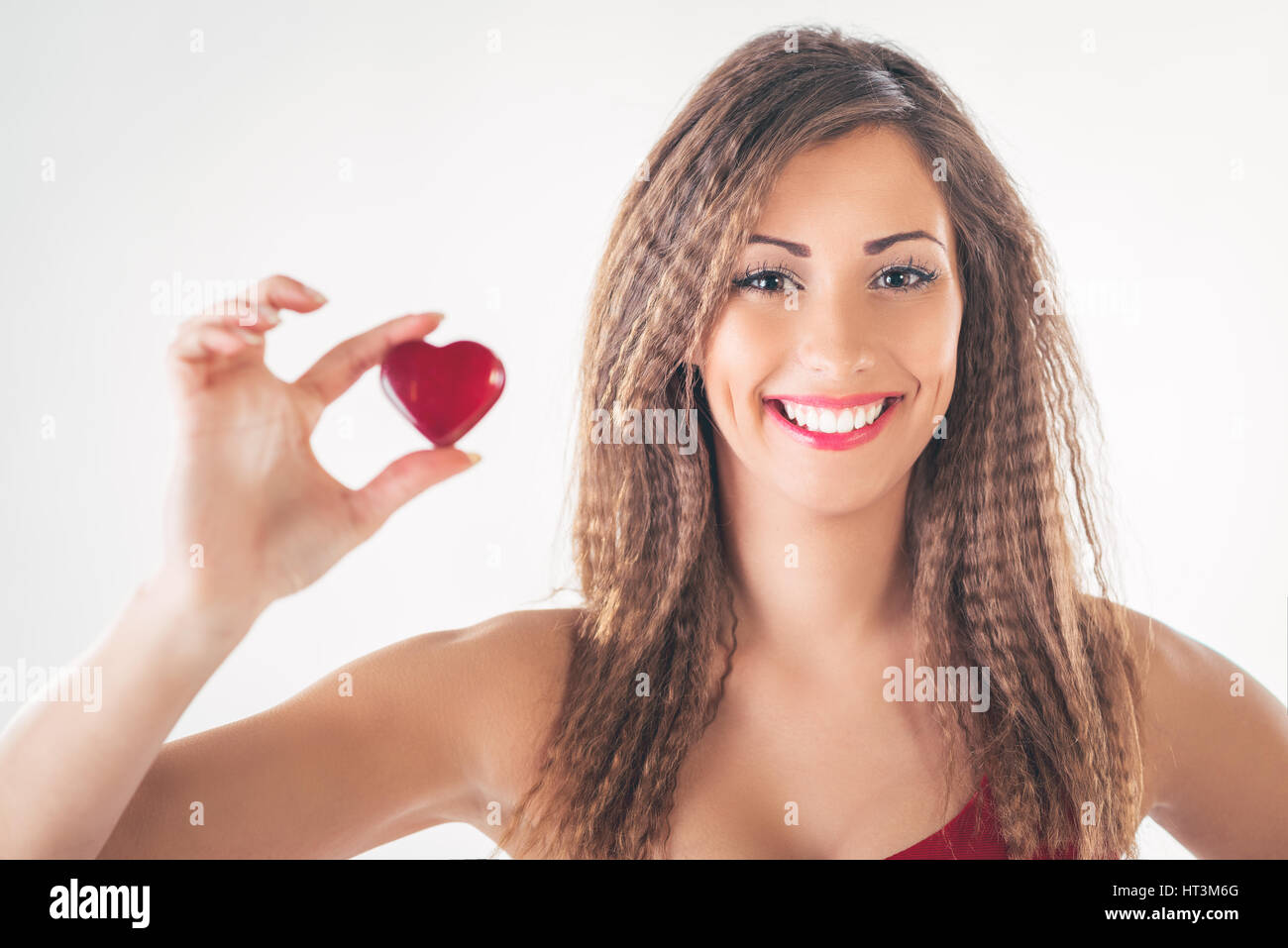 Schönes lächelndes Mädchen hält ein rotes Herz. Selektiven Fokus. Konzentrieren Sie sich auf das Mädchen. Stockfoto