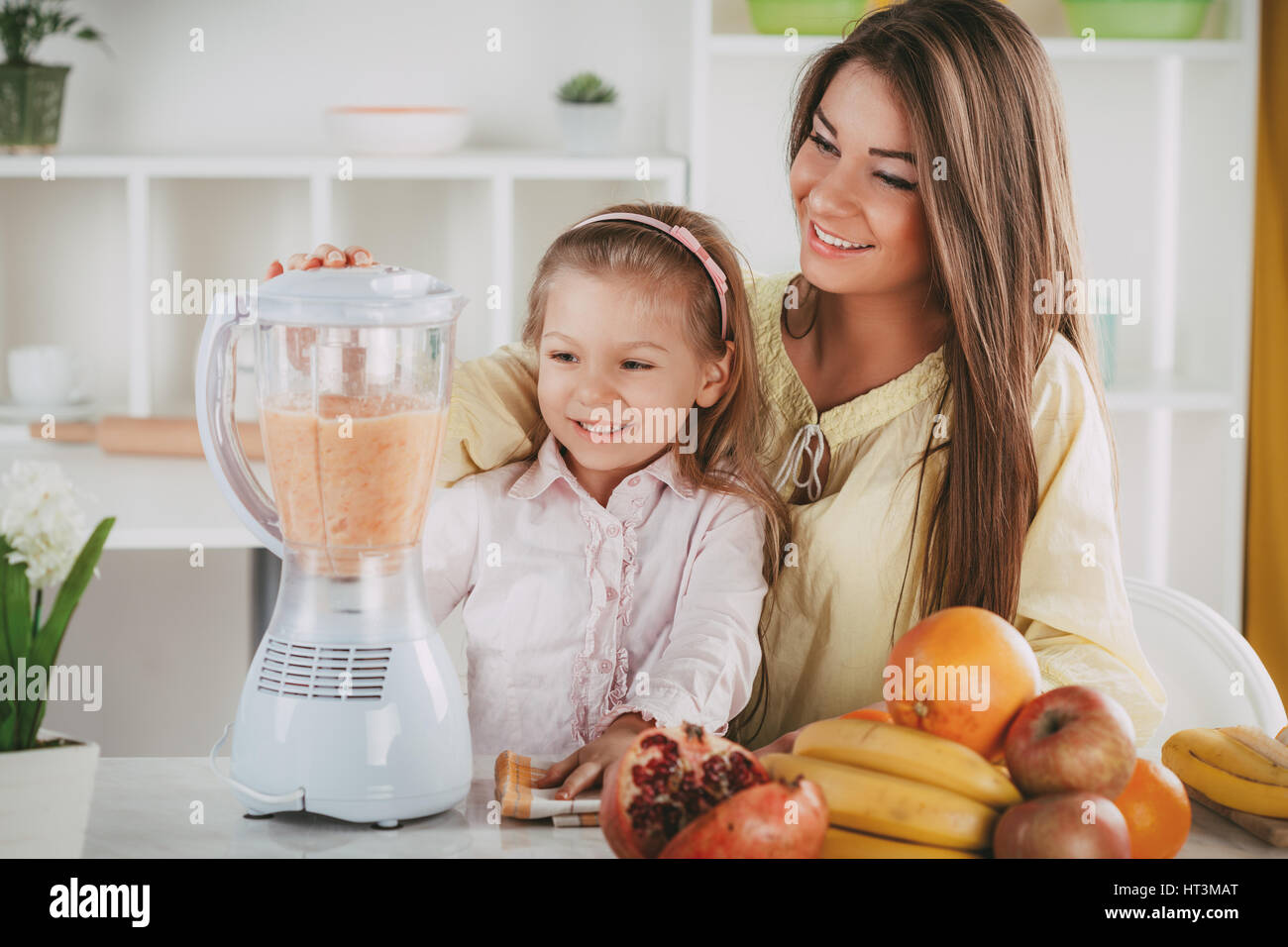 Mutter und Tochter Vorbereitung gesundes Obst Drink oder eine Mahlzeit in einem Mixer in der Küche. Stockfoto