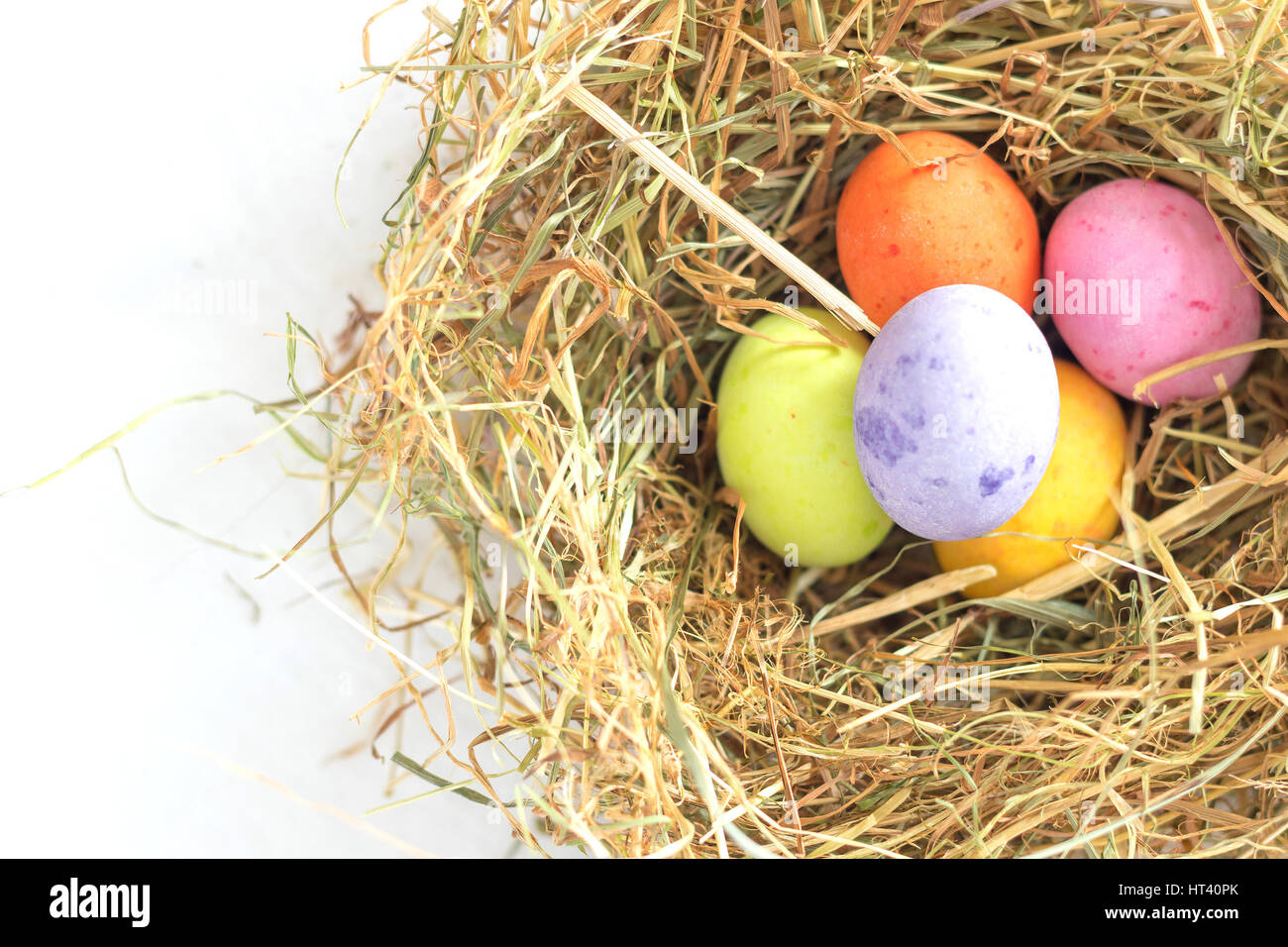 Bunt Pastell Ton Schokoladen-Ostereier in einem Nest aus Stroh in oben auf ein weißes Blatt gemacht Stockfoto