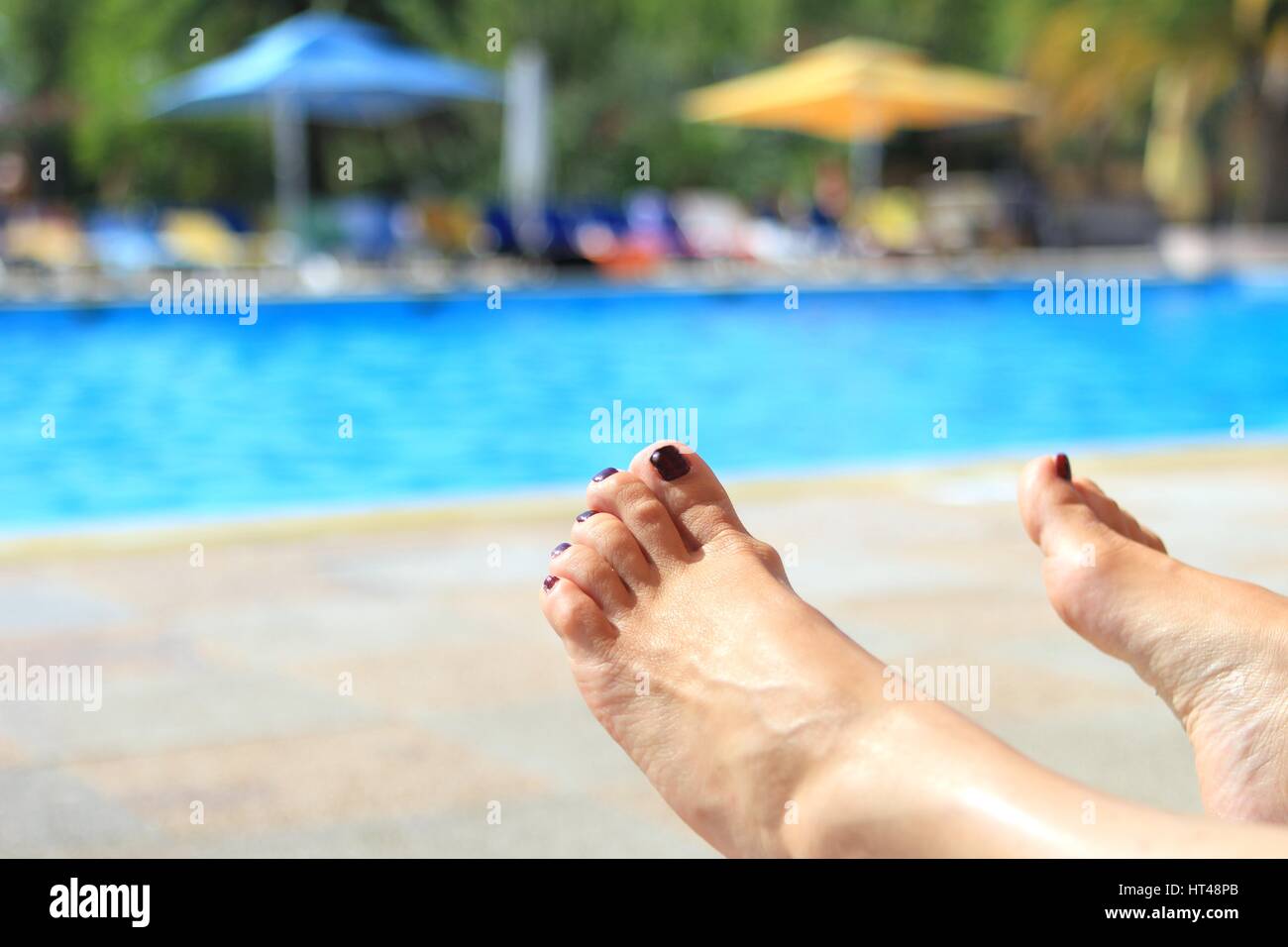 Frau die Füße mit unscharfen sonnigen Pool im Hintergrund Stockfoto