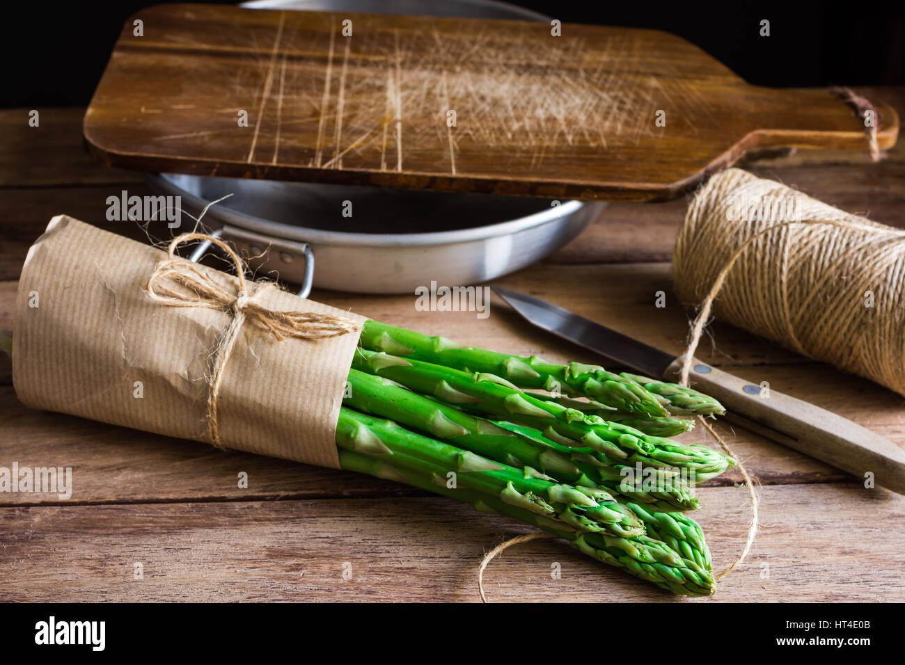 Bündel von frischen Bio Spargel eingewickelt in Kraftpapier am Küchentisch, schneiden, Brett Schale Messer, Tageslicht, gemütliche Atmosphäre Stockfoto