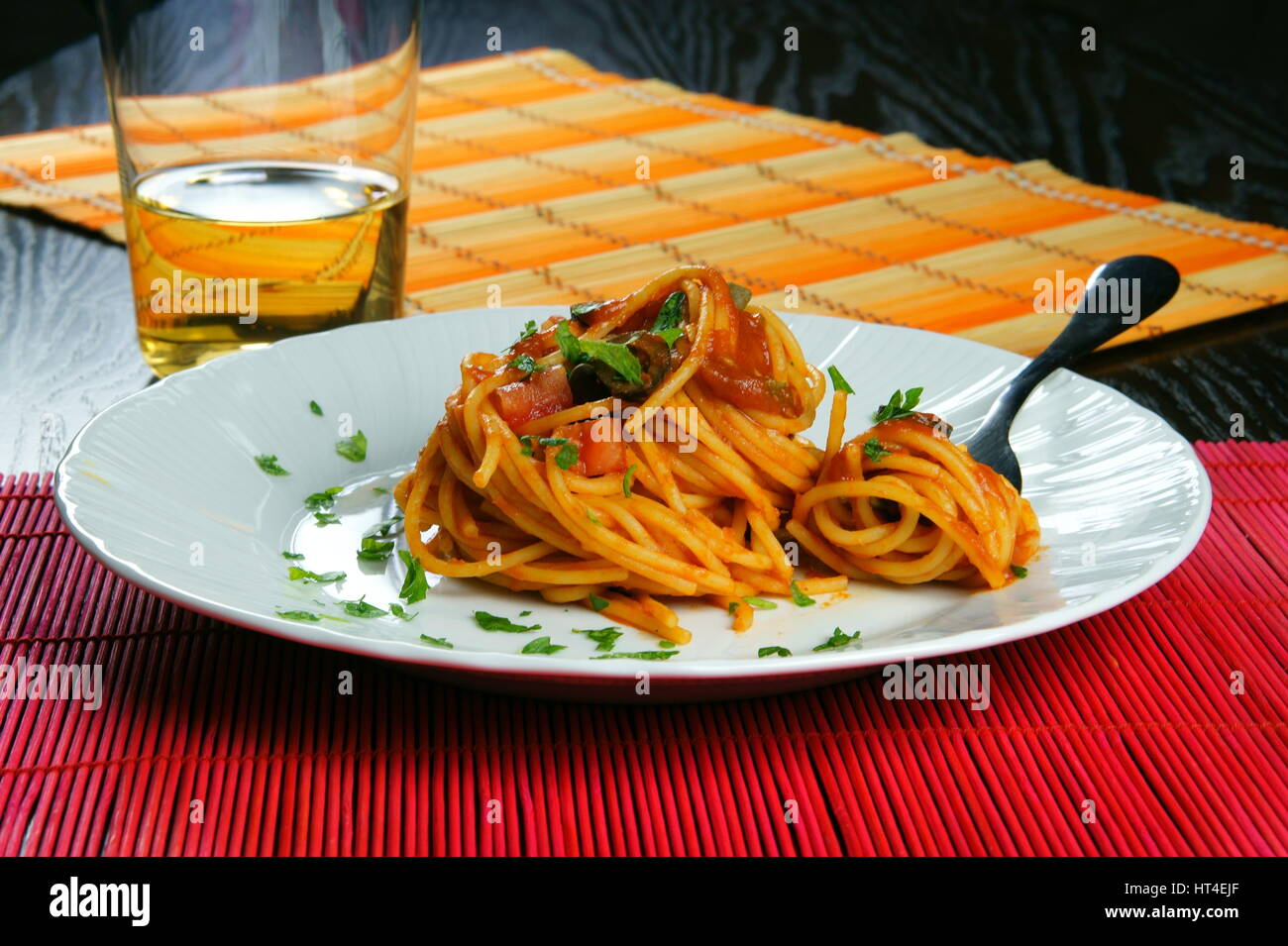 Spaghetti Puttanesca mit Gabel serviert in einer weißen Schale - italienisches Rezept mit Knoblauch, Olivenöl, Sardellen, Oliven, Tomaten, Petersilie, Kapern Stockfoto