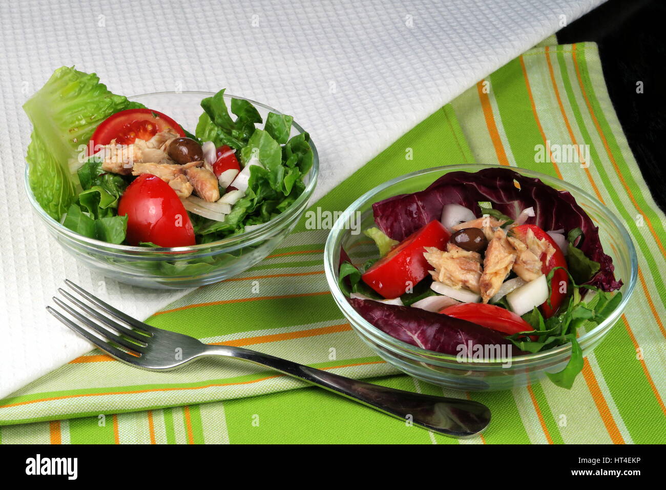 Kopfsalat, Tomaten, Oliven und Makrele Sommersalat serviert in Glasschalen auf bunten Küchentuch mit Gabel - gesunde Nahrung für grüne Wohnzimmer Stockfoto