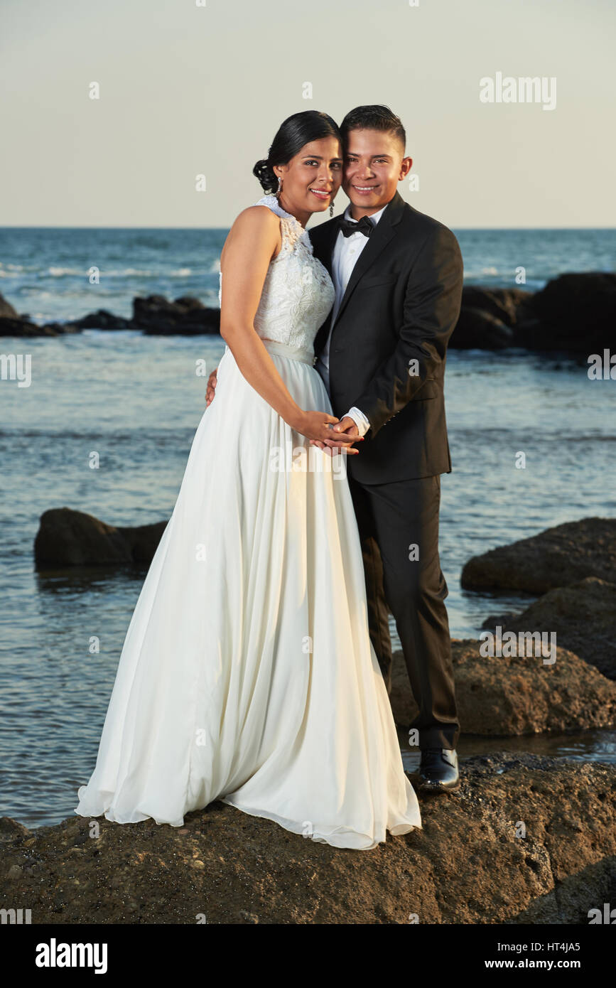 Hochzeit am Meer Küste von Hispanic paar. Junge Braut und Bräutigam stehen auf Stein Felsen Stockfoto
