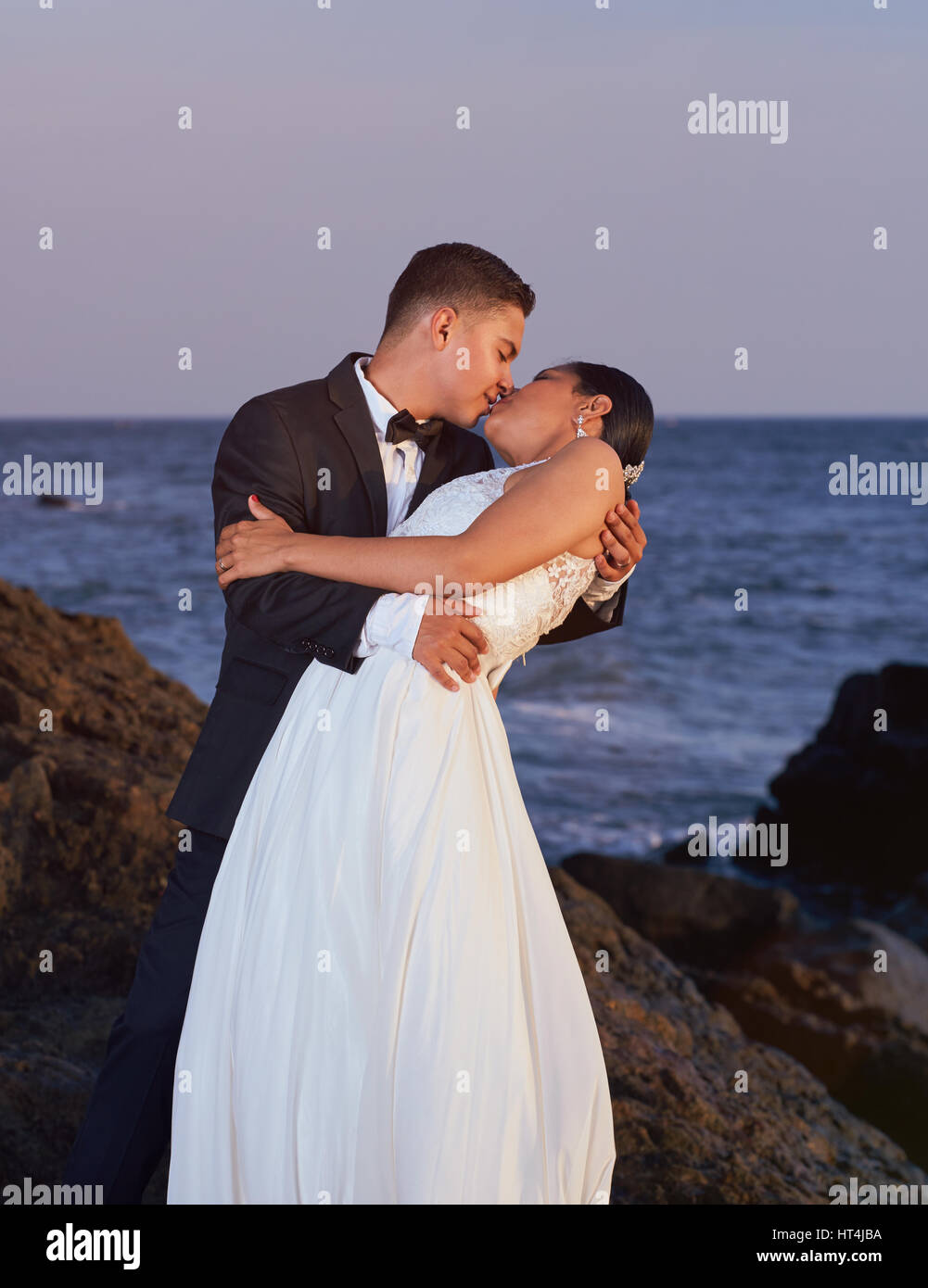 Braut und Bräutigam küssen am Strand Sonnenuntergang. Hochzeitspaar umarmen am Ozean Stockfoto
