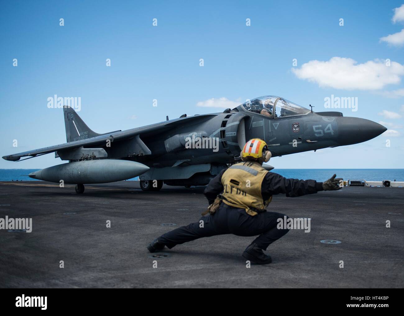 Ein US-Seemann Signale einem U.S. Marine Corps AV-8 b Harrier II Kämpfer Flugzeug für aus dem Flugdeck auf dem USN Wasp-Klasse amphibischer Angriff Schiff USS Makin Island 10. Februar 2017 im Persischen Golf abheben. Stockfoto