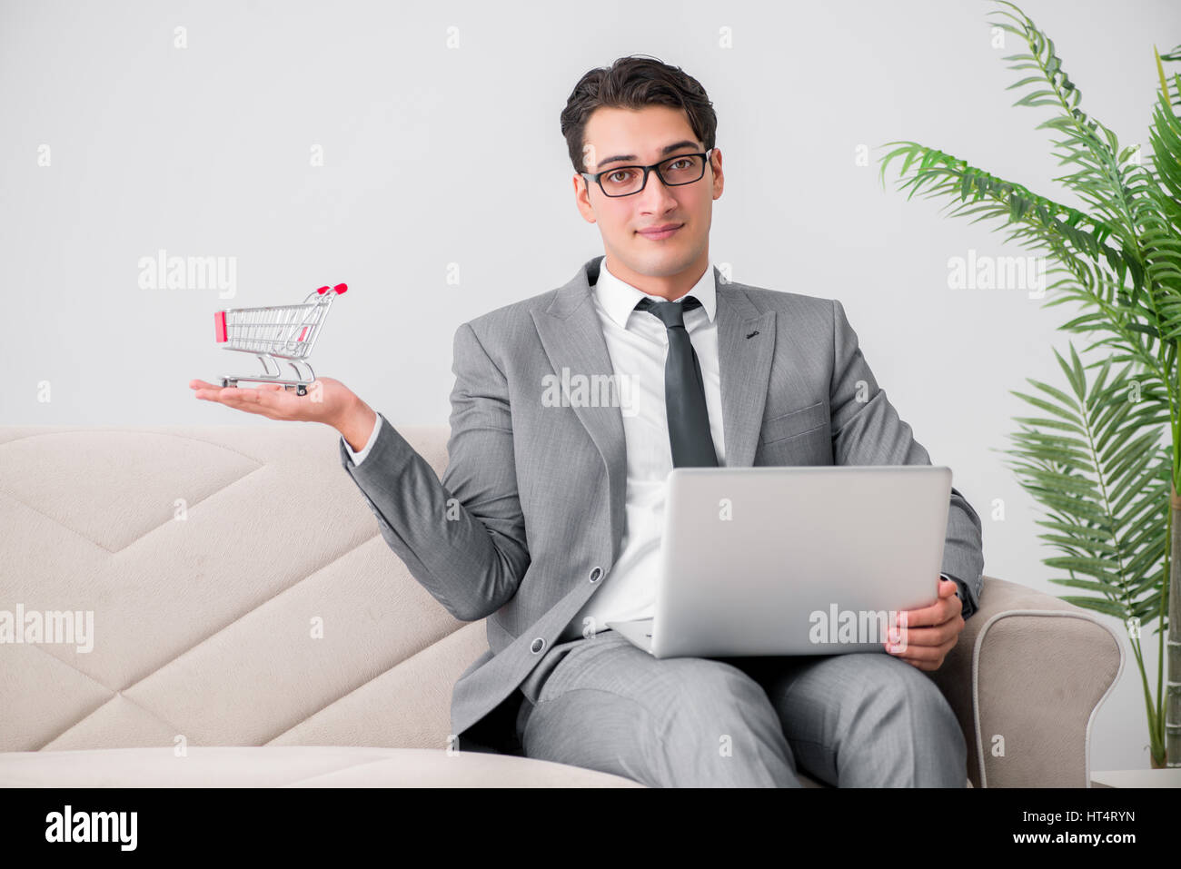 Geschäftsmann mit Laptop und Warenkorb Stockfoto