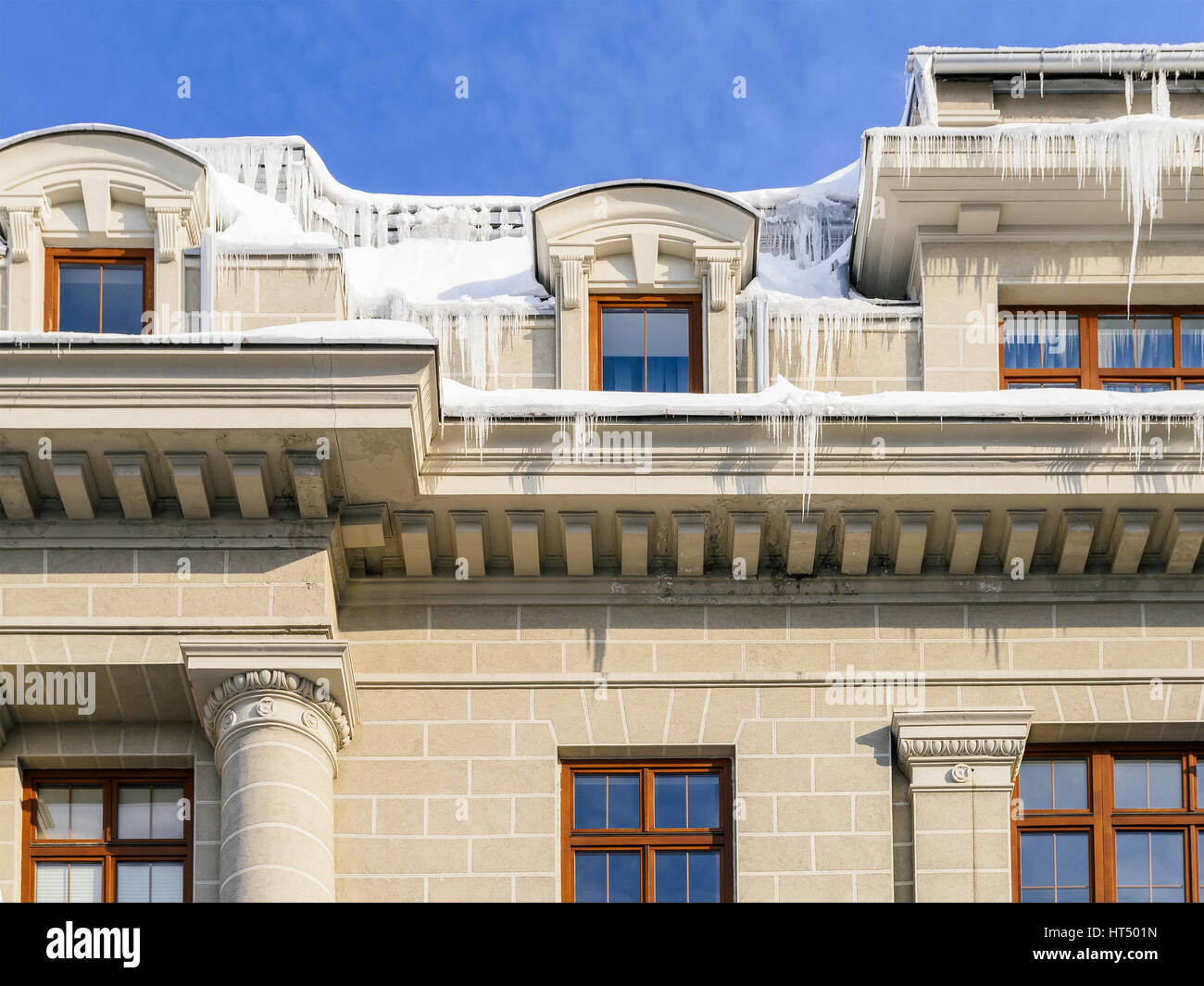 Hausdach bedeckt mit Schnee und gefährliche Eiszapfen Stockfoto