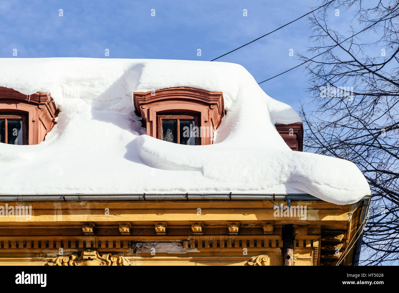 Hausdach bedeckt mit Schnee und gefährliche Eiszapfen Stockfoto