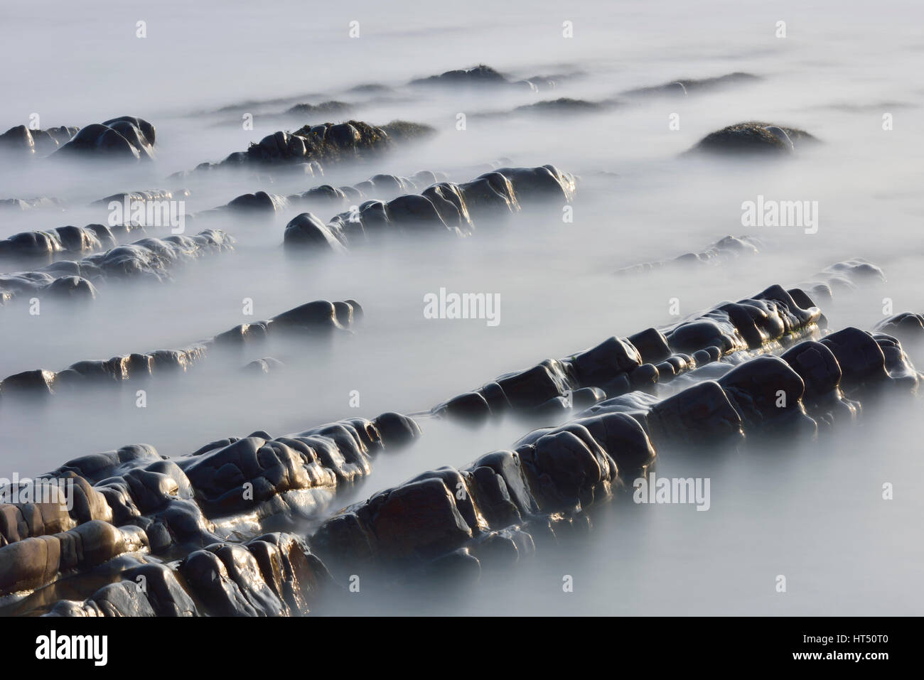 Felsformationen im Meer, Langzeitbelichtung, Atlantikküste in der Nähe von Bude, Cornwall, Vereinigtes Königreich Stockfoto