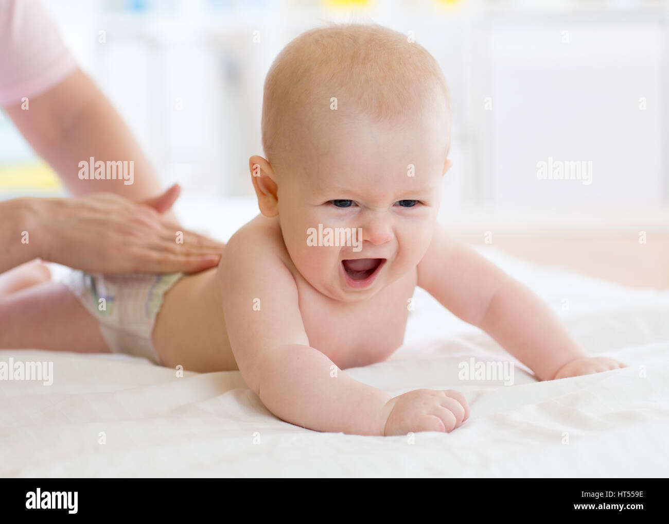 Frau Arzt Massage Baby im Bett im Kinderzimmer Stockfoto