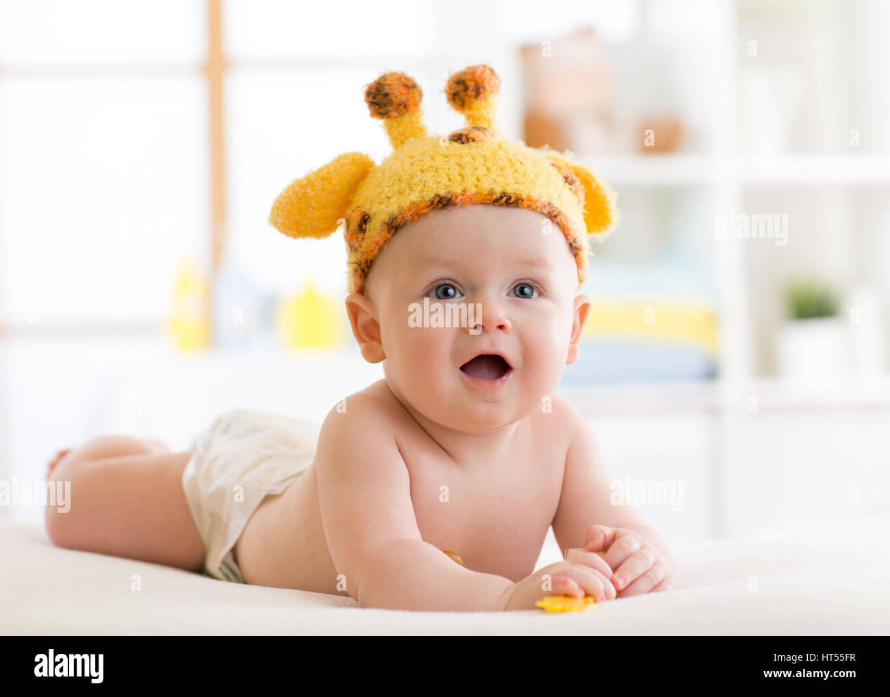 Baby Boy in lustige Giraffe Hut liegen auf dem Bauch im Kindergarten Stockfoto