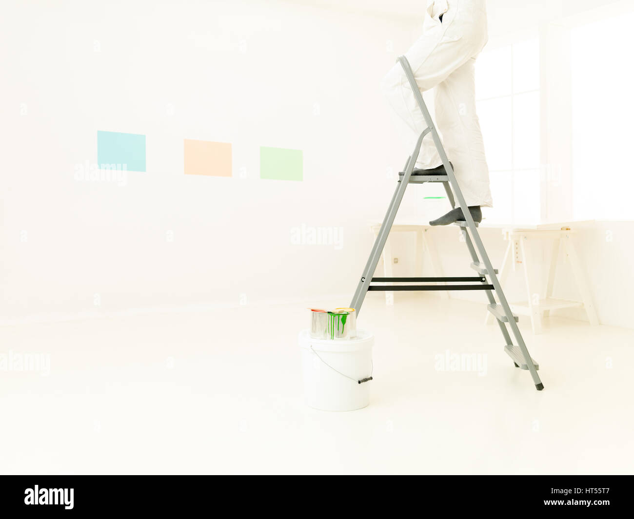 Die Beine des Mannes auf die Trittleiter Malerei, helle weiße Haus. Reparatur, Bau, Renovierung und Menschen-Konzept Stockfoto