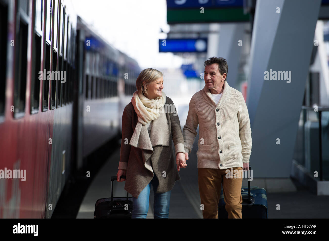 Schönes älteres Paar am Bahnhof ziehen eine Trolley-Gepäck. Stockfoto