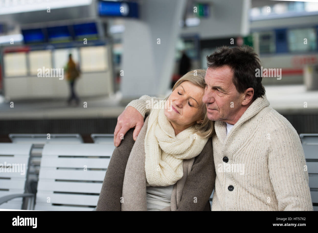 Schönes älteres paar warten am Bahnhof, sitzen auf Bank, umarmen Stockfoto