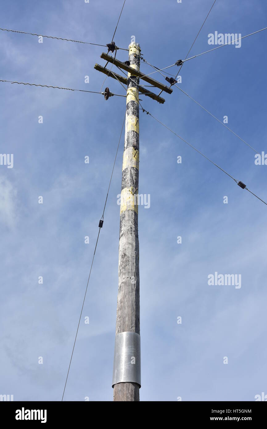 Hohe Sonne gebleicht hölzernen Strommast mit ein paar Drähten. Stockfoto